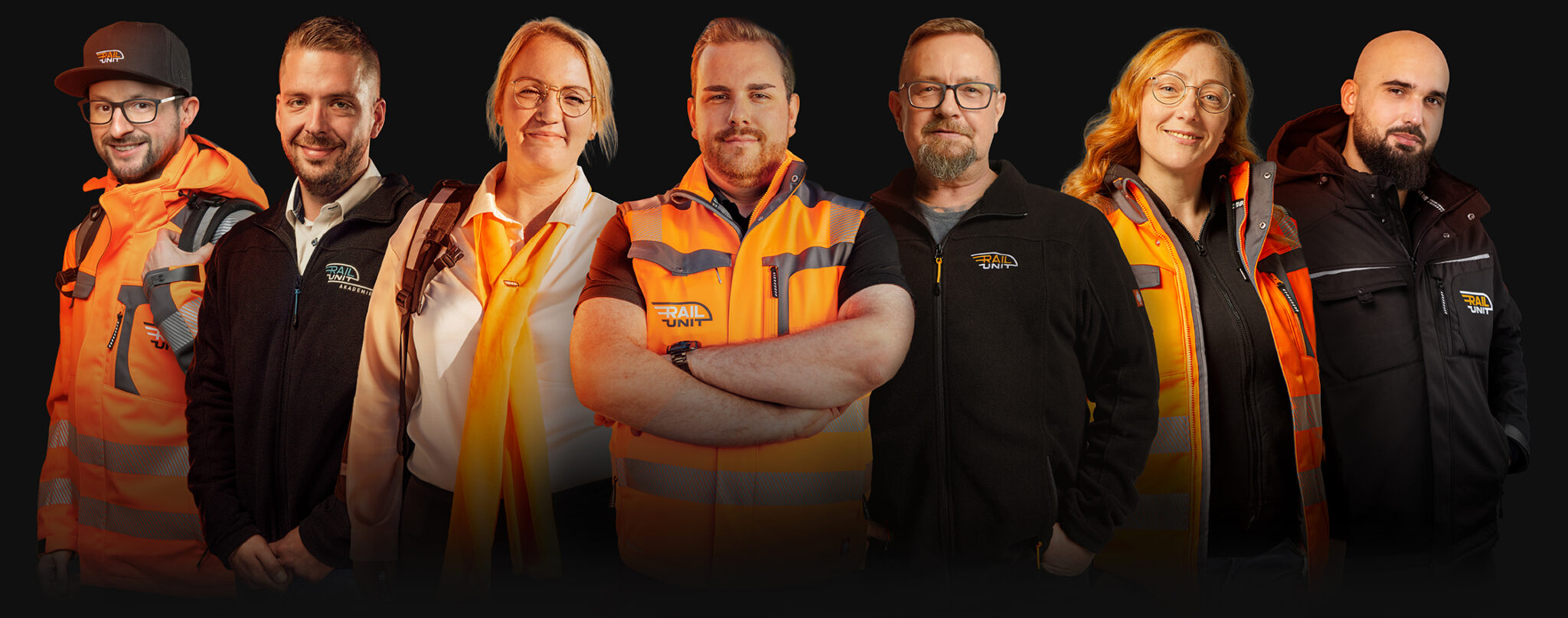 Collage mehrerer Rail-Unit-Teammitglieder, die in Arbeits- und Firmenkleidung lächelnd nebeneinander stehen.